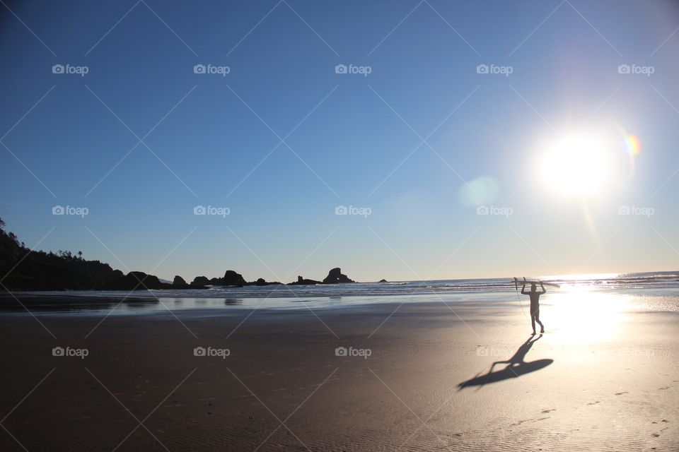Surfer on beach in sunset