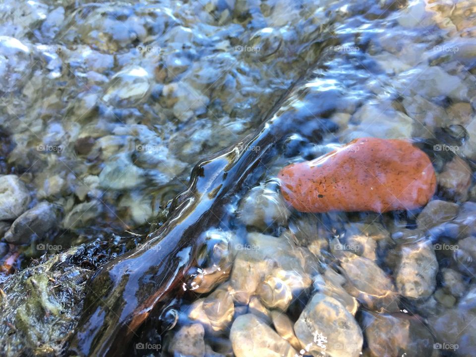 Tranquility and relaxation water moving over an orange pebble in water abstract zen and nature power of water in motion photography 