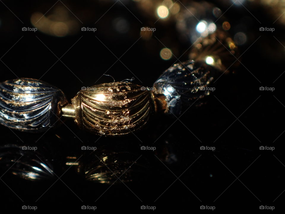 Cliseup image of gold bracelet on reflective surface isolated on black background