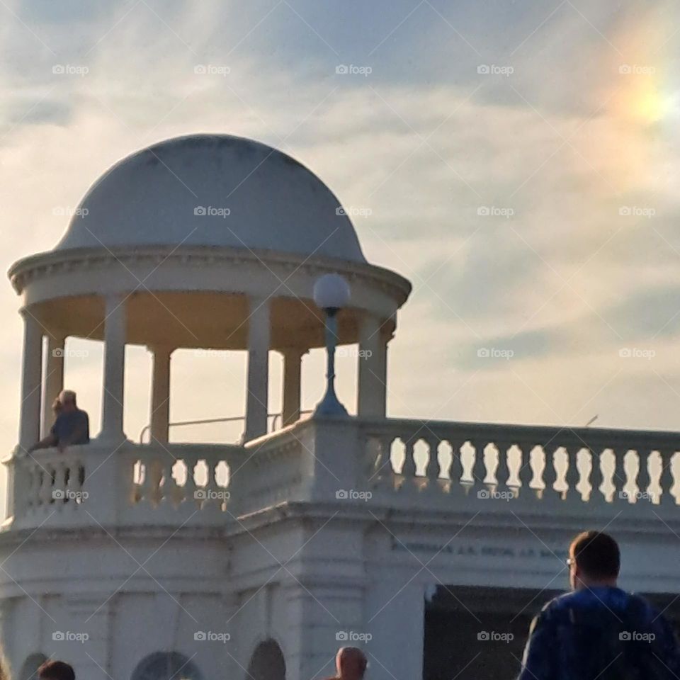 white domed building summer evening sky. small rainbow colours people
