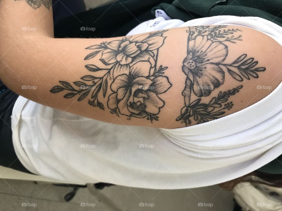 Tatuaje floreado en brazo de mujer joven 