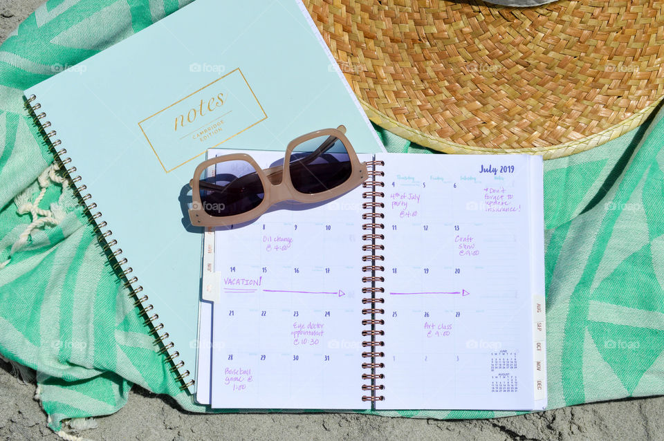 Planner and sunglasses laid out on the beach