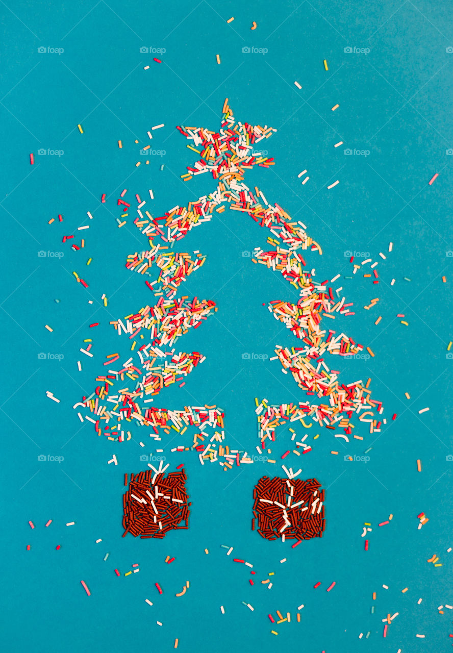 Christmas tree. Symbols of christmas tree and gifts made of colored sprinkles on blue background