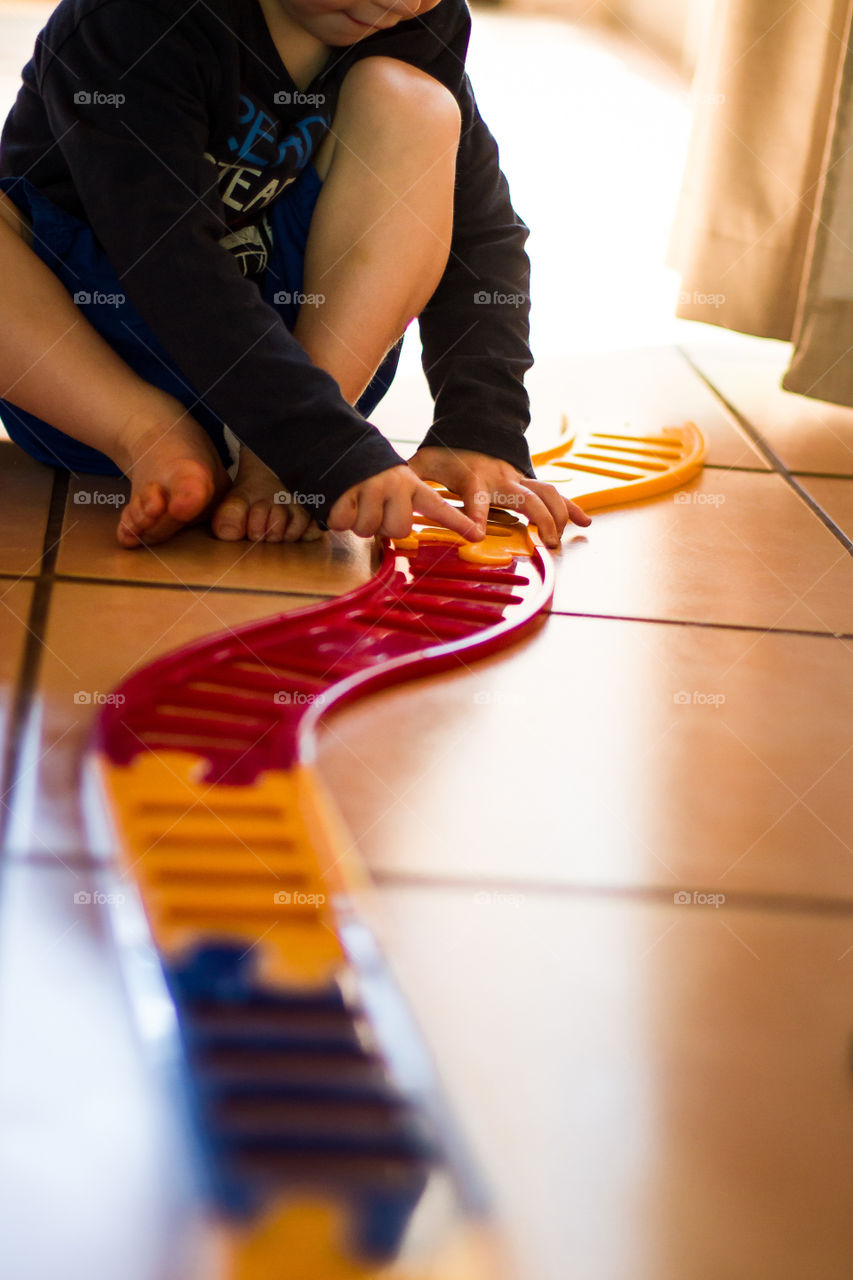 Build and play - boy putting together train tracks to play with at home