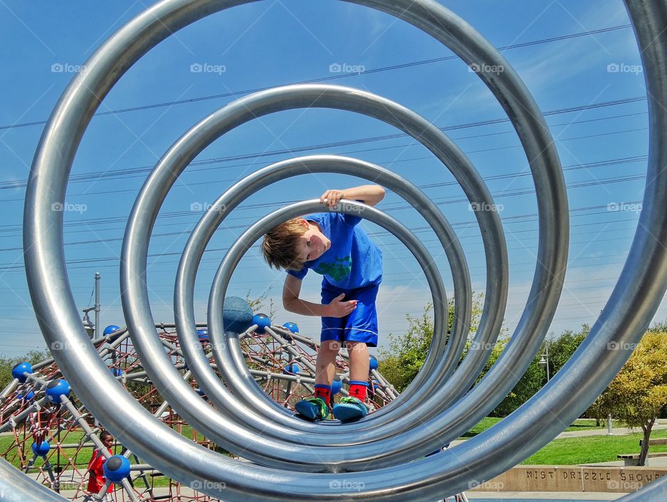 Spiral Shape. Young Boy Playing On A Metal Spiral Statue
