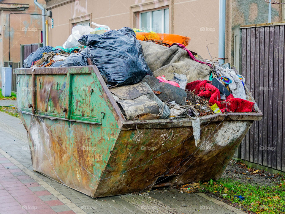 a large metal waste container on the citys street, full of waste