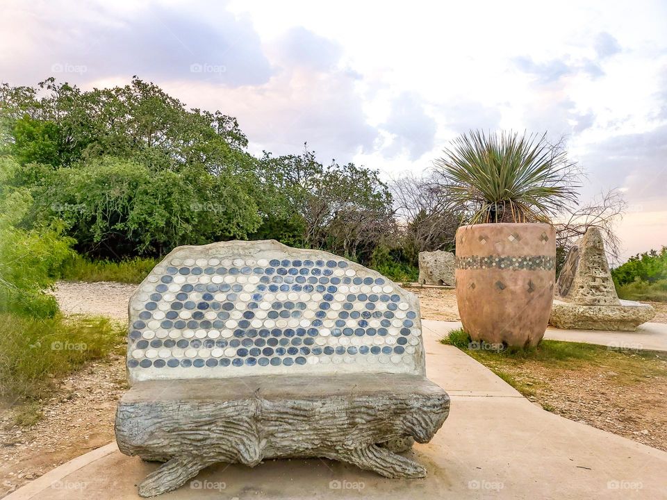 Public visual urban art inspired by Native American cultures at city park.Sculpture and bench.
