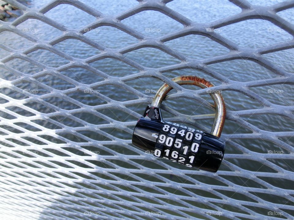 Coded lock hanging on the fence of the bridge