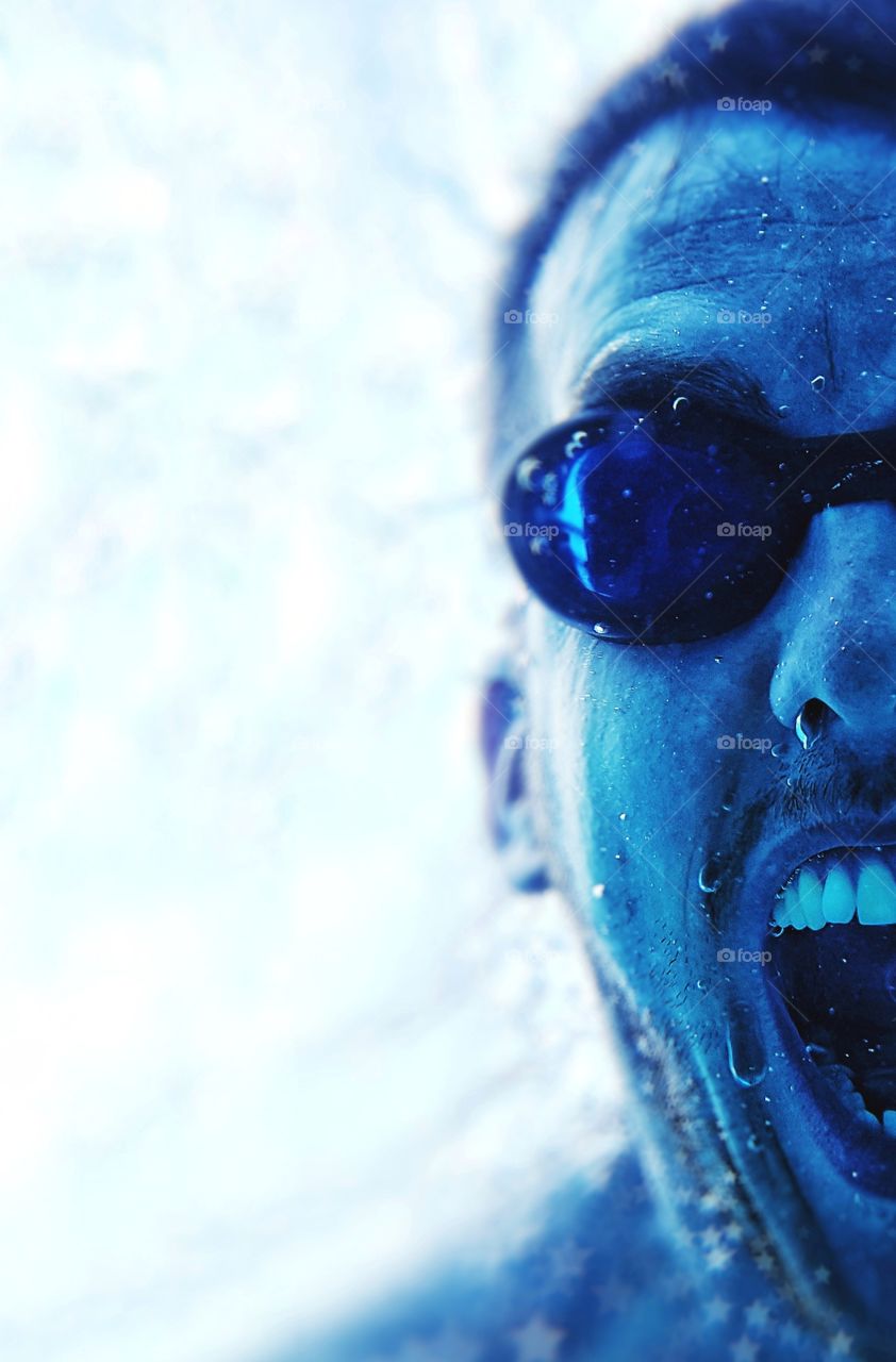 close up half face portrait of man underwater blue tones