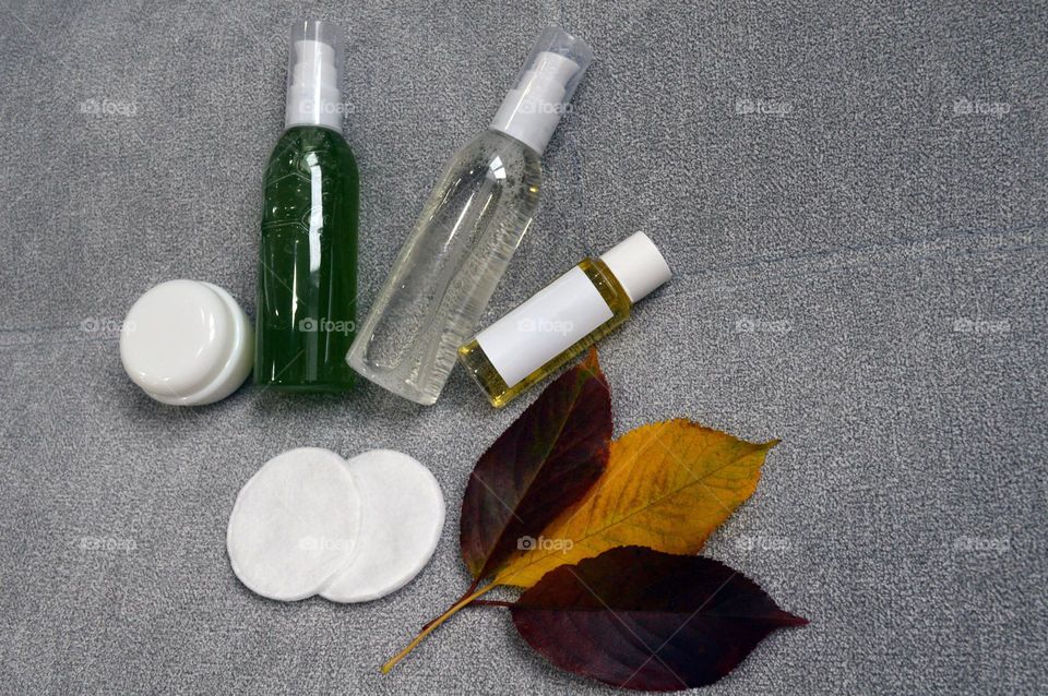 Jars with cream, shampoo and cosmetics on a background with autumn leaves