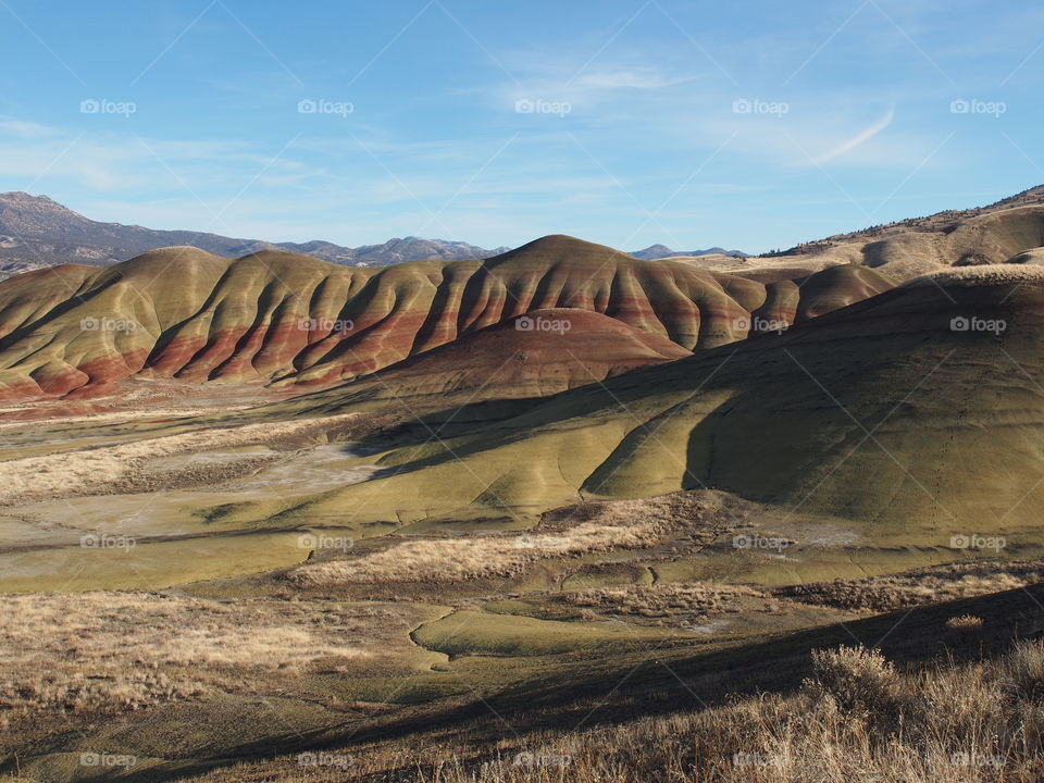 The incredible beauty of the red, gold, and browns of the textured Painted Hills in Eastern Oregon on a bright sunny day.