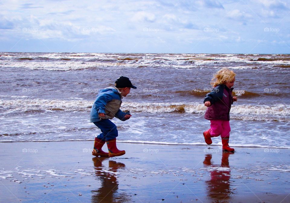 Happy time. Two children run from the waves