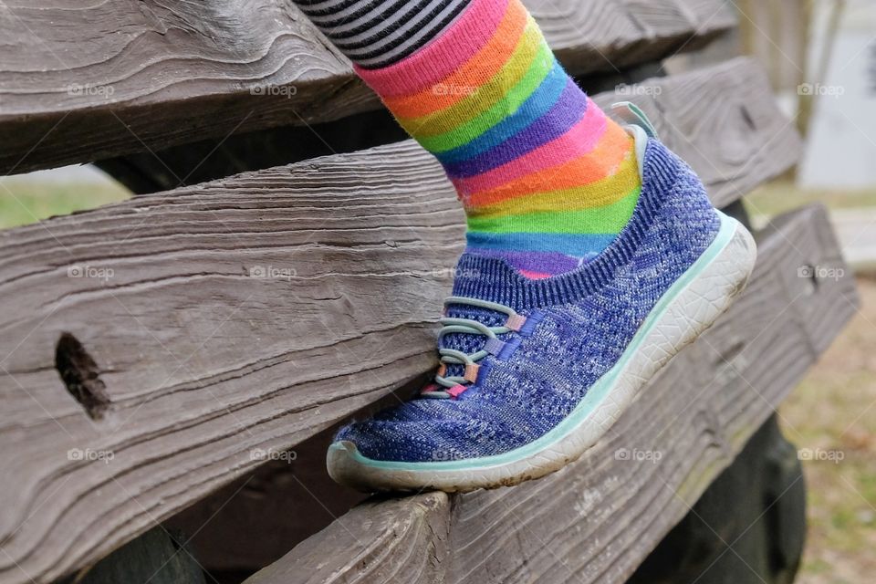 The foot of a little girl climbing at the playground wearing colorful socks and shoes. 