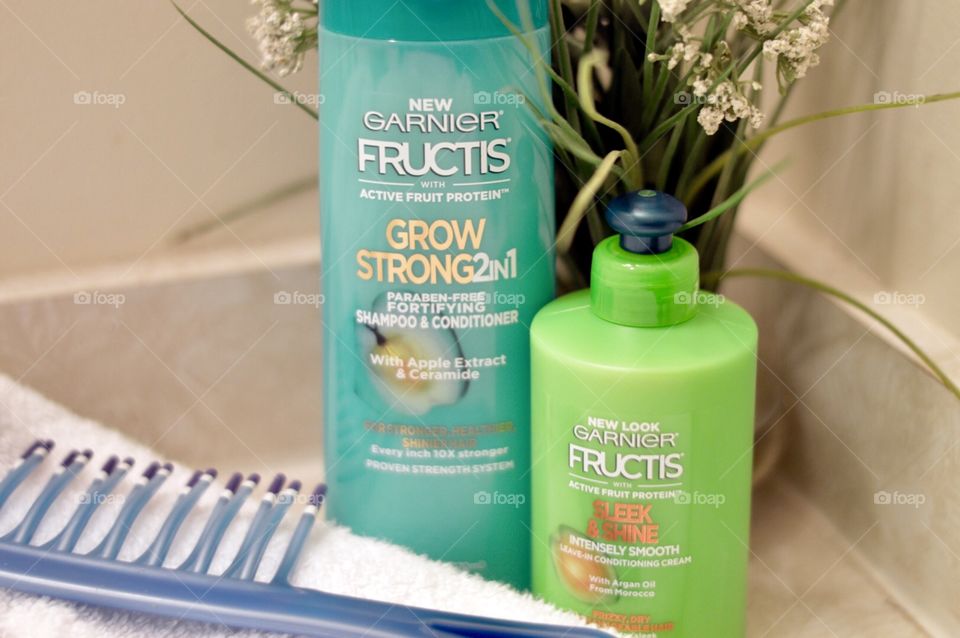 Garnier two in one shampoo and conditioner and anti-frizz or a bathroom countertop with a white towel and a comb