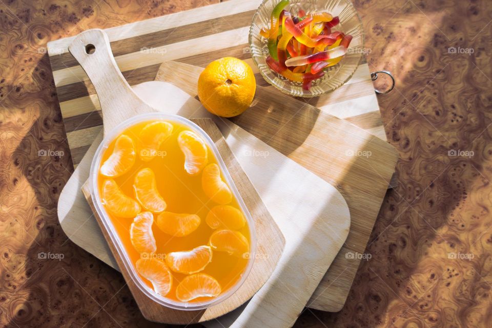 Delicious orange jelly with tangerine slices in a container and jelly worms.