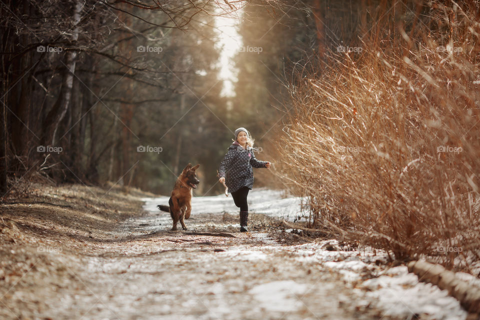 Girl walking with German shepherd puppy in a spring forest 