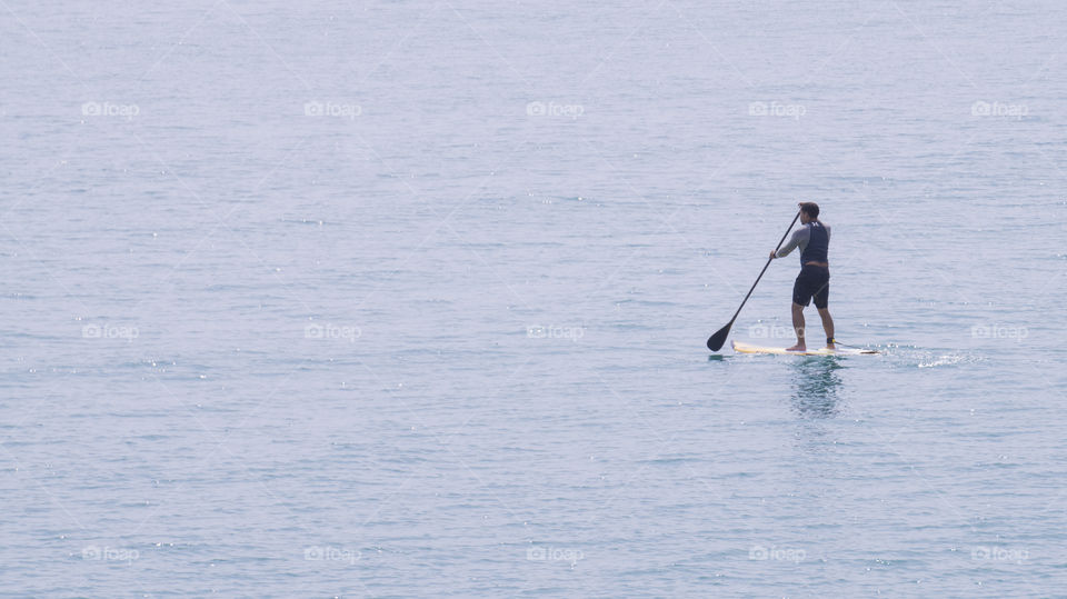 A man takes to the ocean to go paddle boarding in summer