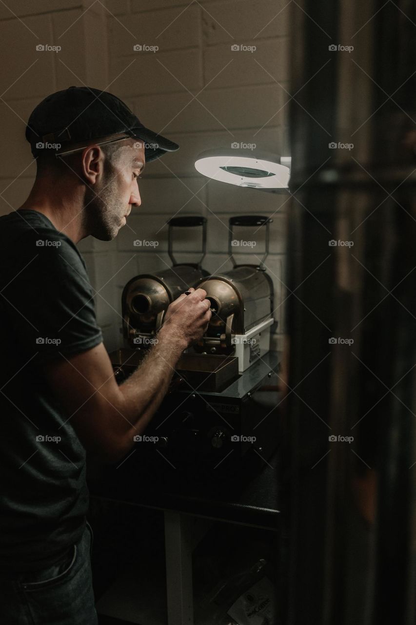 Coffee roaster sampling coffee beans from small roaster.