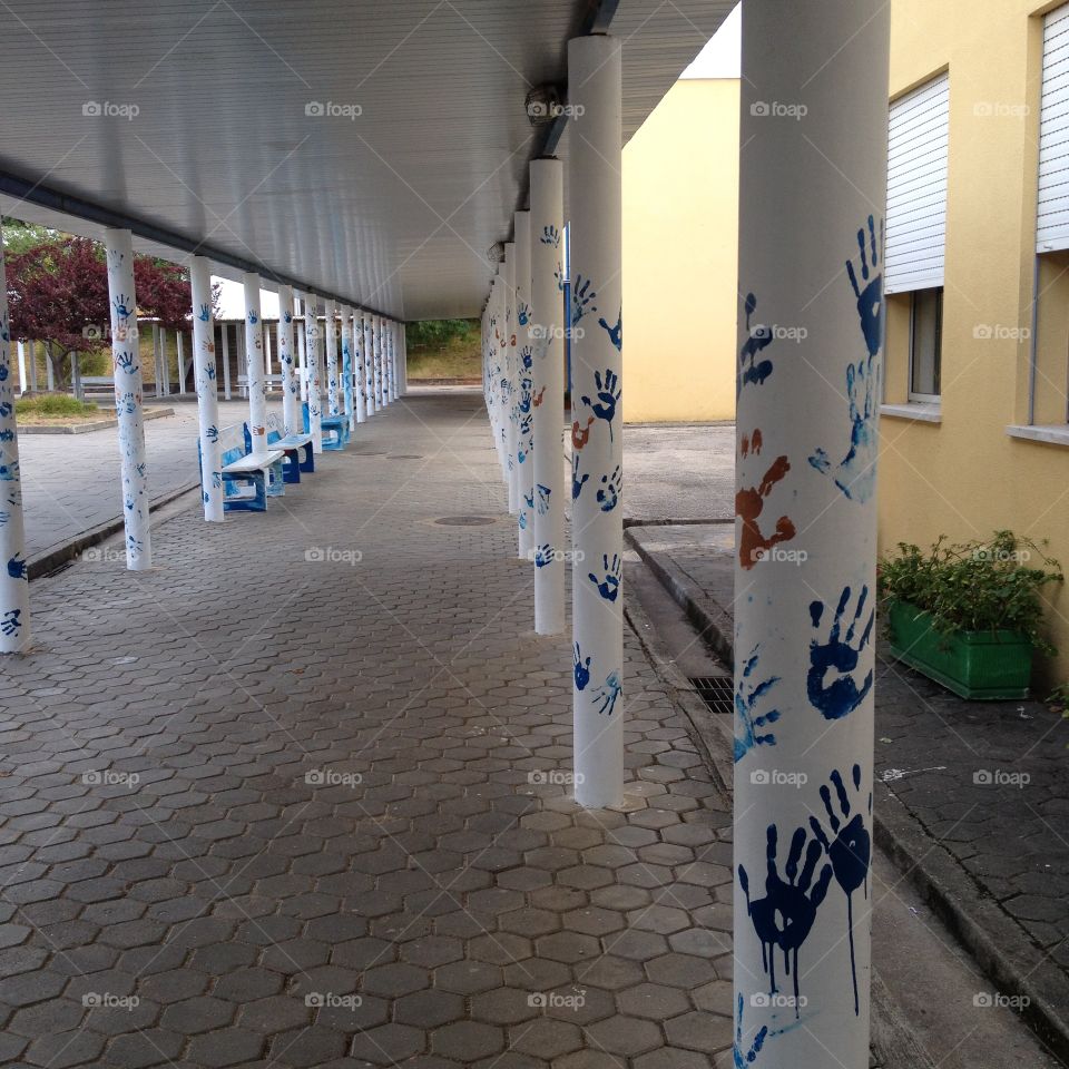 School alley with columns decorated with painted hands 