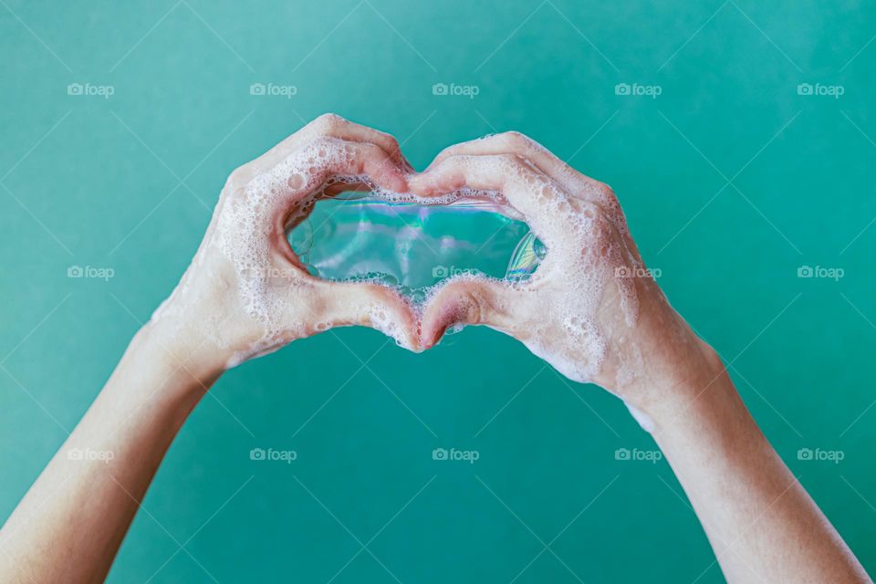 hands and soap foam at the mint green background