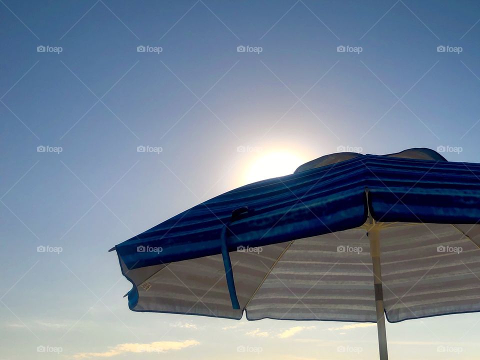Warm sun behind beach umbrella 