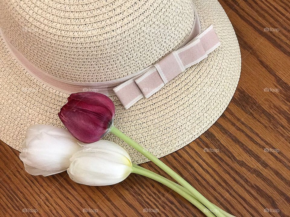 Hat with flowers on wooden table