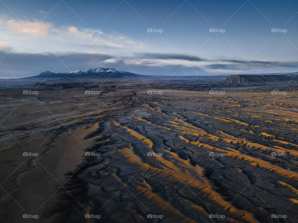 Lines of the desert landscape lead towards mountains on the horizon during sunrise