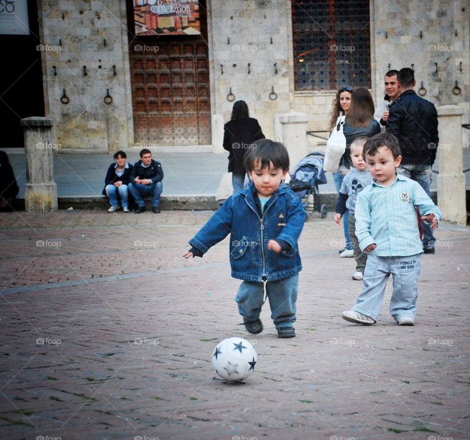 Kick it. Two toddlers focus their play on a little soccer ball