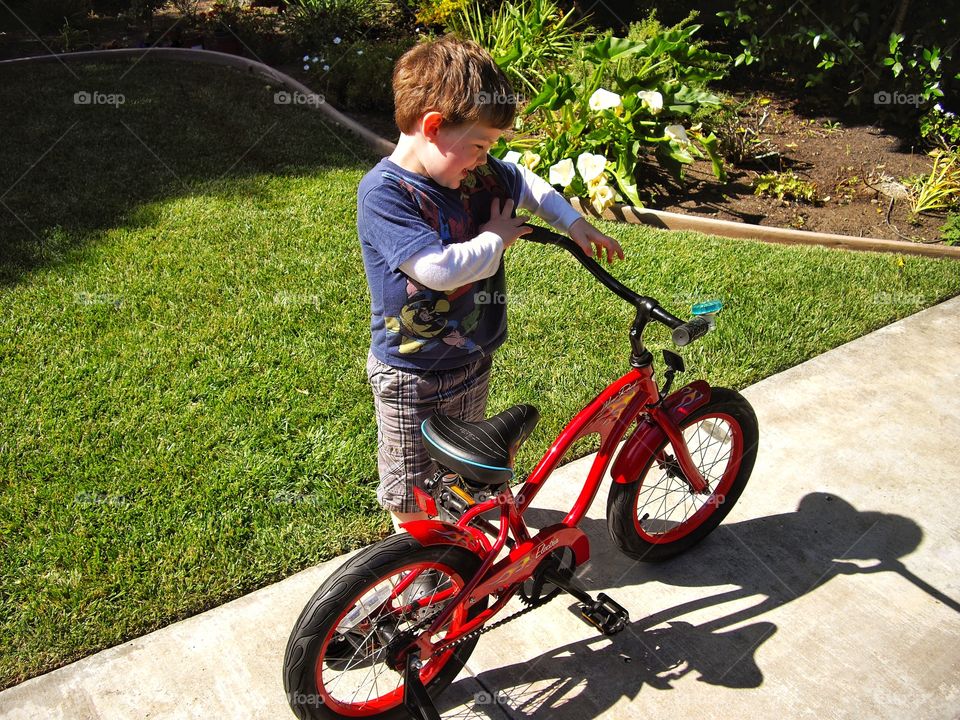 Young Boy Proud Of His Shiny Red Bike
