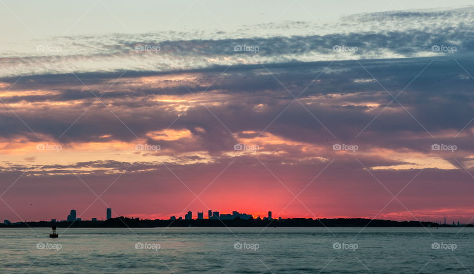 Vibrant sunset over the Atlantic Ocean with the Boston skyline silhouette 