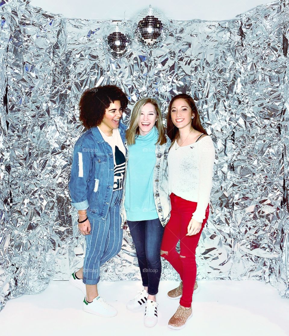 Three beautiful young women laughing and enjoying their time together in a magical ice castle photobooth