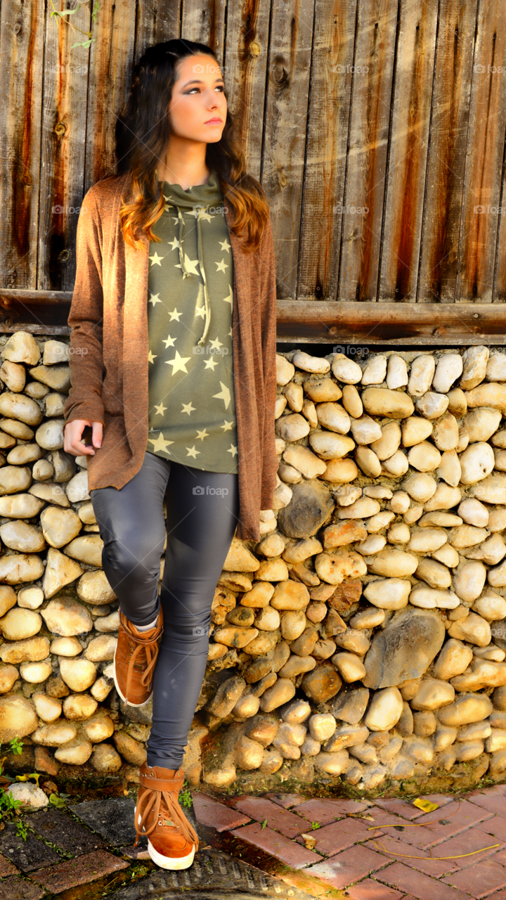 Young beautiful woman leaning against pebble wall