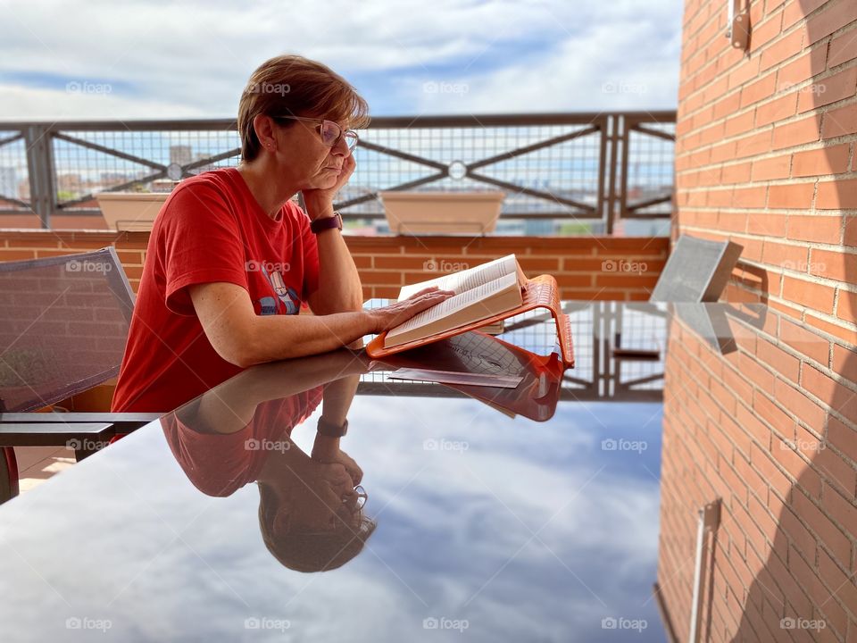 Woman reading a book at a glass table