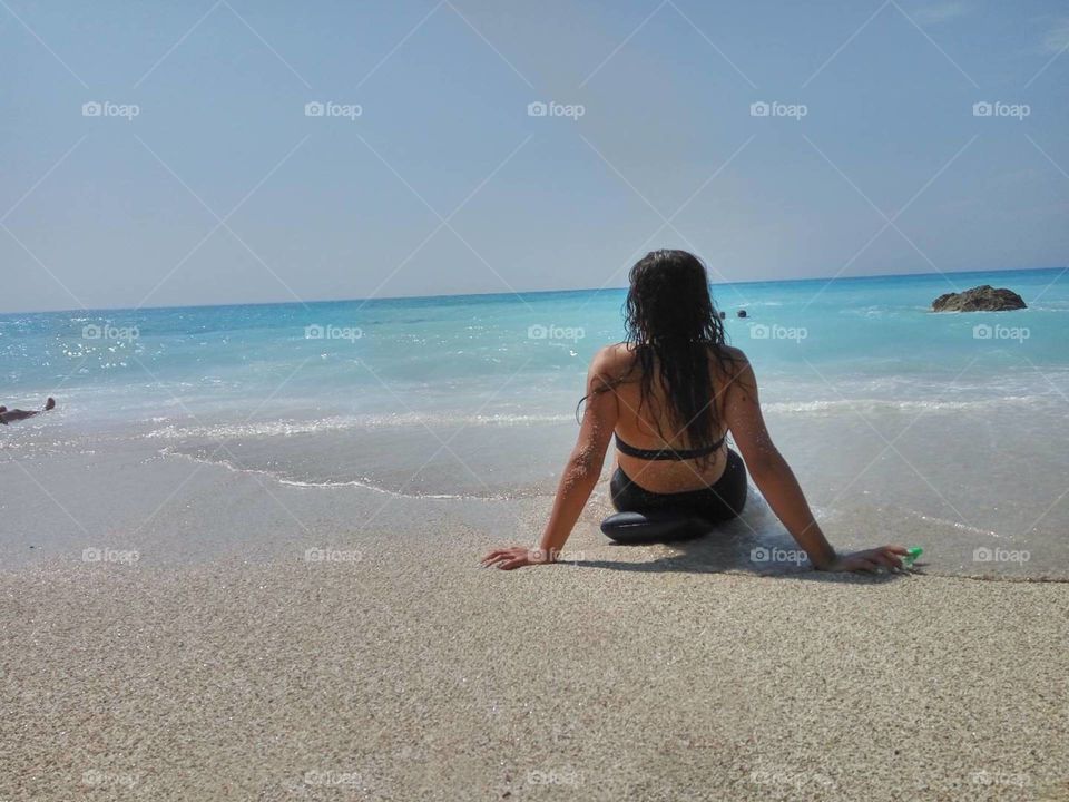 A brunette girl on the sand by the beach, while the sun is shining and the waves are washing down all that hurts inside