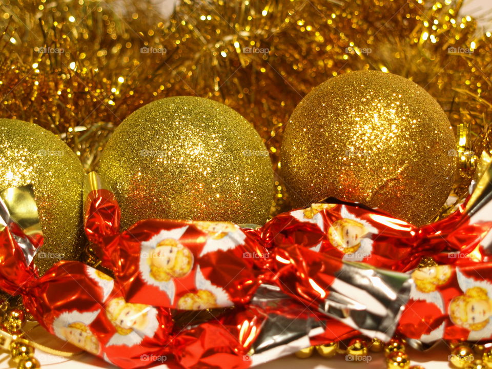 Holidays background close up with gold tinsels, ball decorations, beadwork and christmas candy.