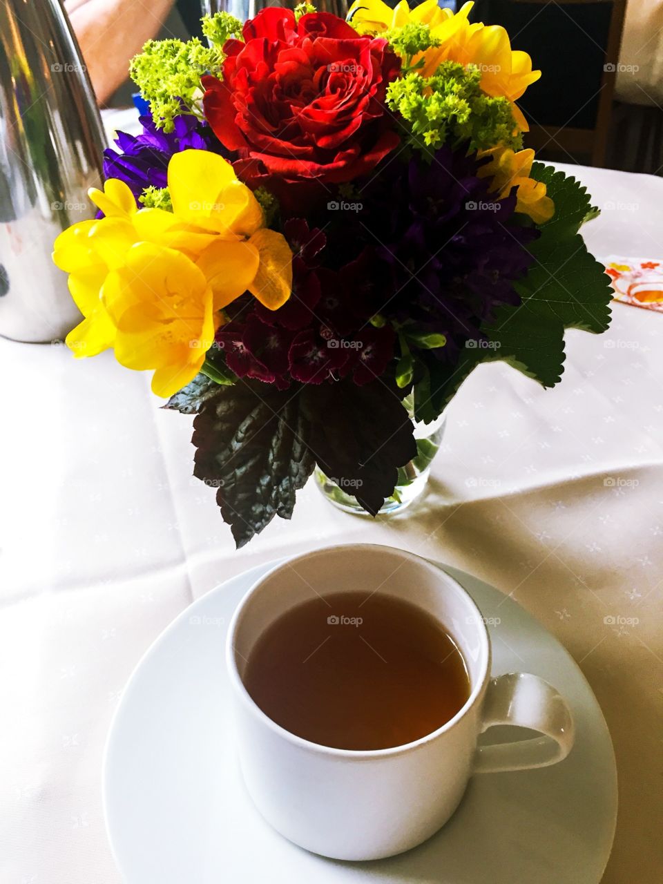 1 white hot tea cup and colorful flower vase on the table , relaxing time . I’m talking with my family 