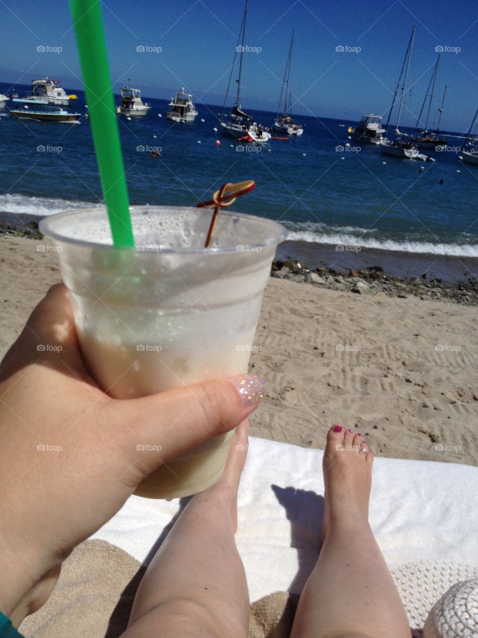 Tropical Drink in my hand and laying on the sand.