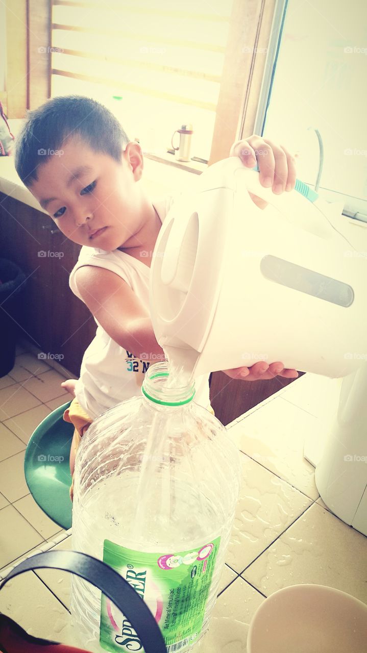 Asian boy pouring water in the bottle