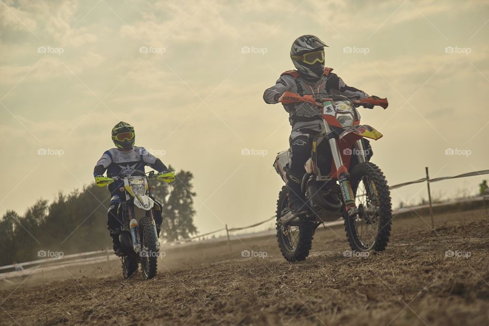 Pair of enduro riders whizzing along the race track, chasing and fighting for the first position.