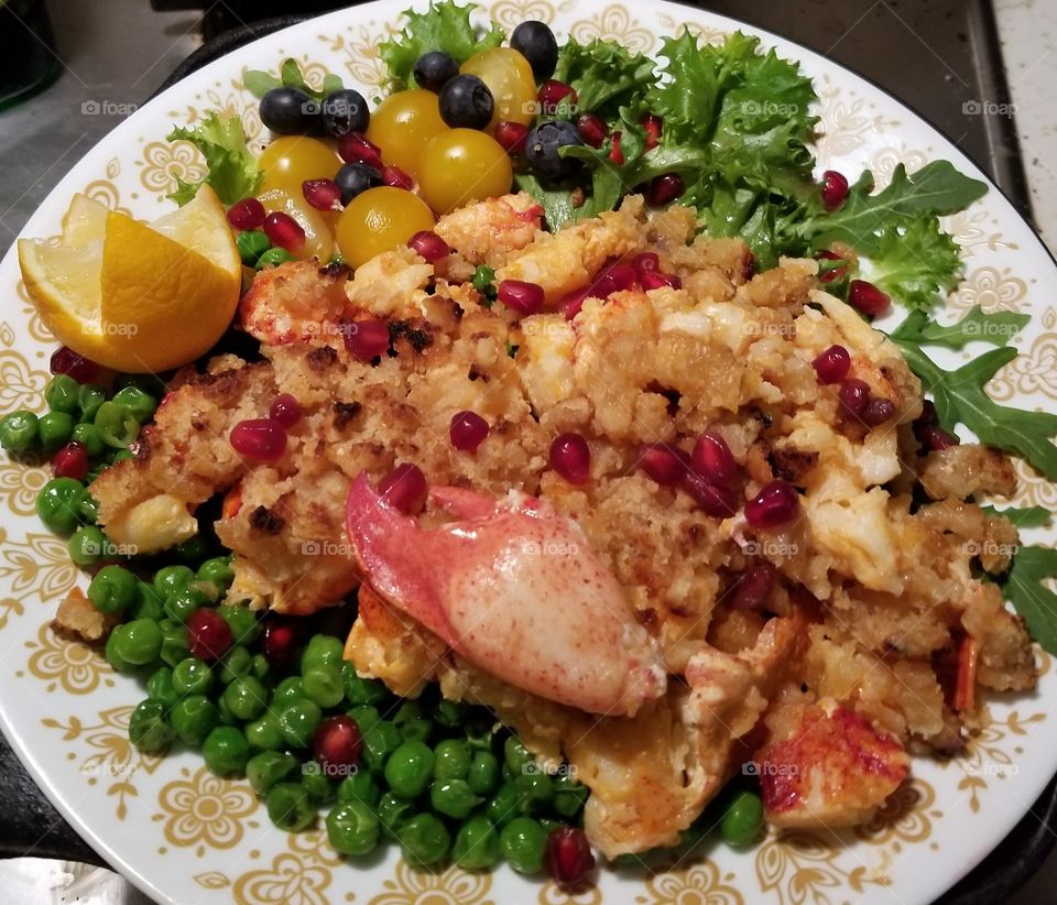 Christmas eve dinner at home on Cape Cod. Lazy lobster and stuffing, drizzled with butter and  meyer lemon. Served with fresh English peas, cherry tomatoes, arugula, and sprinkled with pomegranate arils and fresh blueberries.