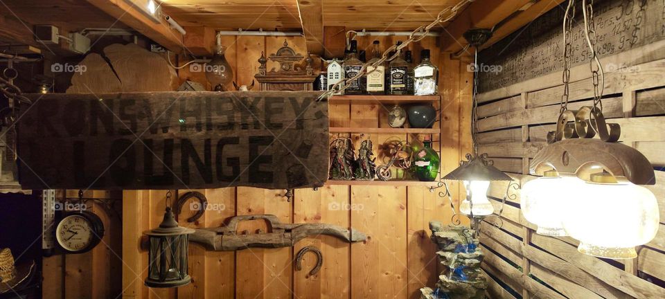 This is the inside of “Ron’s Whiskey Lounge”. Rustic with wooden walls, bows & arrows for shooting and “Jack Daniels” on the top shelf this place reminds of the pioneering days of the old West. 2023. Hypnotic Productions
