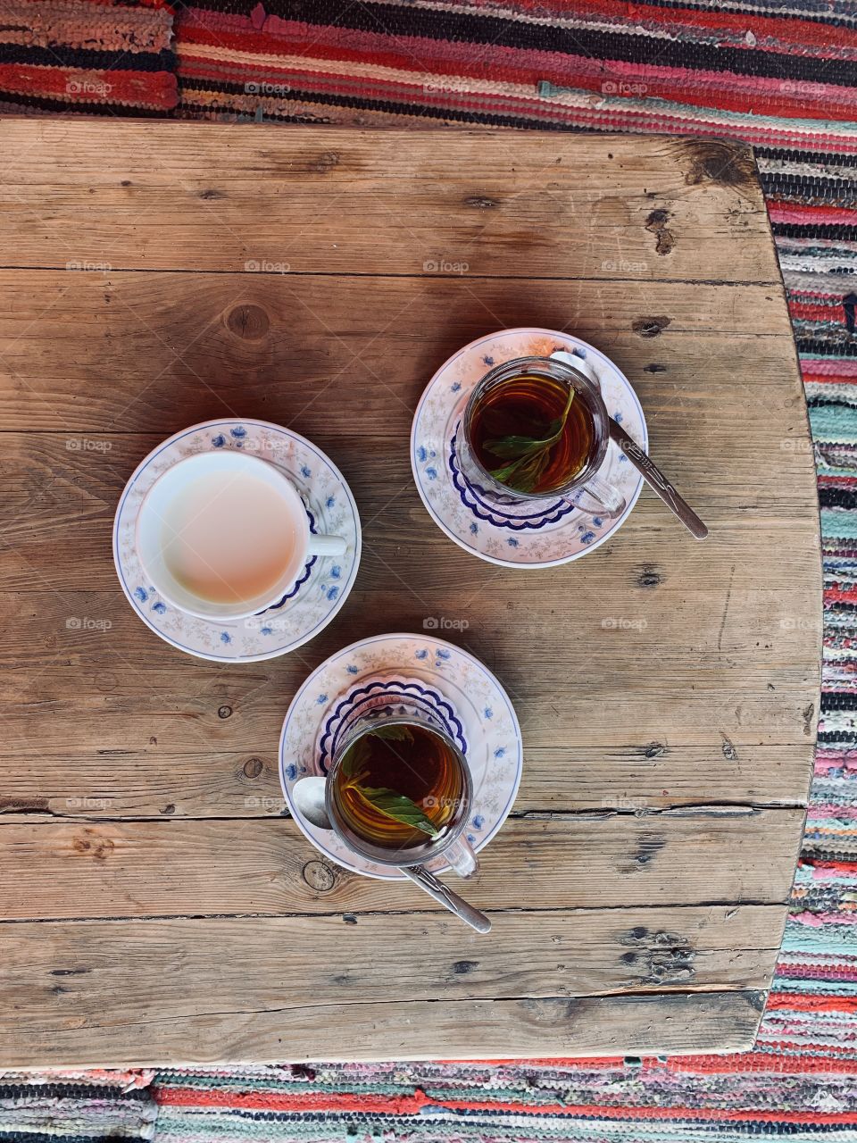 Three cups with mint tea and milk at wooden table top view 