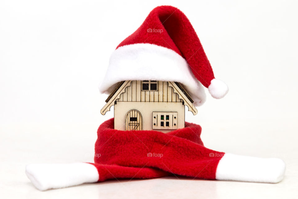 toy wooden house in a red cap of Santa Claus in a red scarf on a white background