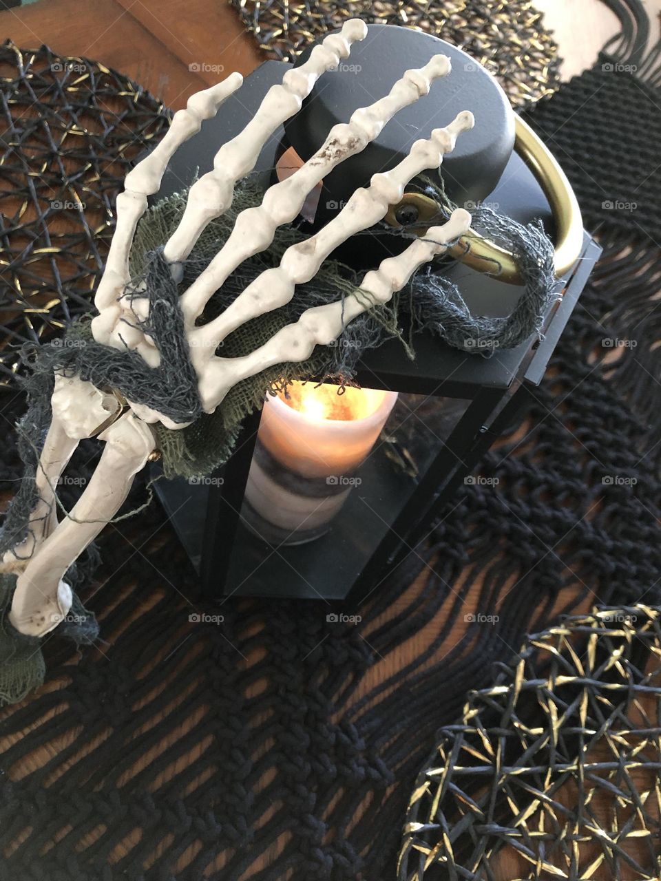 Skeleton hand on lantern with candle for Halloween 