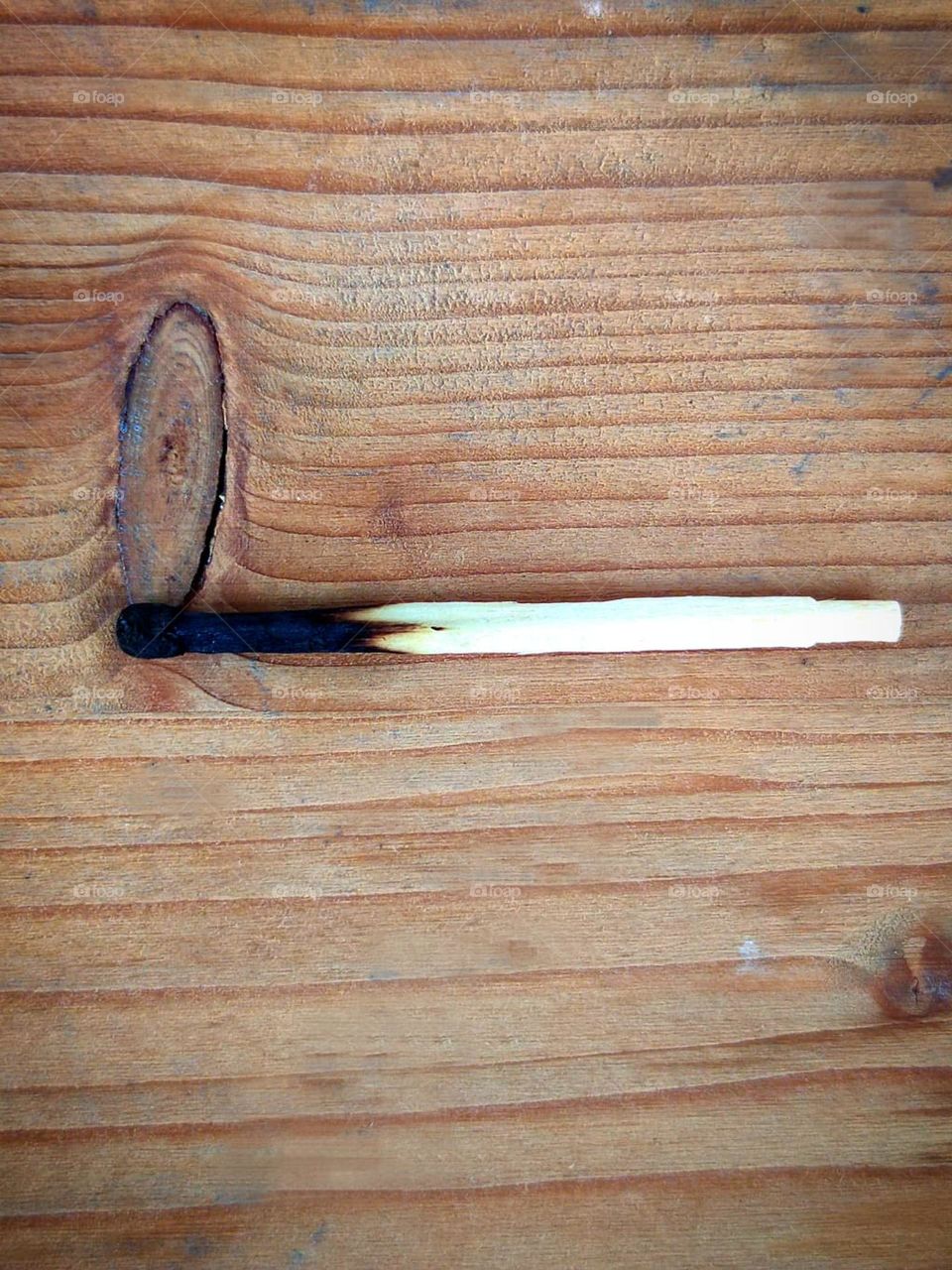 The wooden background lies an extinguished match on a ring of wood in the shape of a flame
