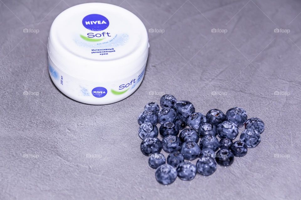 Cosmetic Nivea skin care product on a gray surface with a fresh, fragrant blueberry lined with a heart.