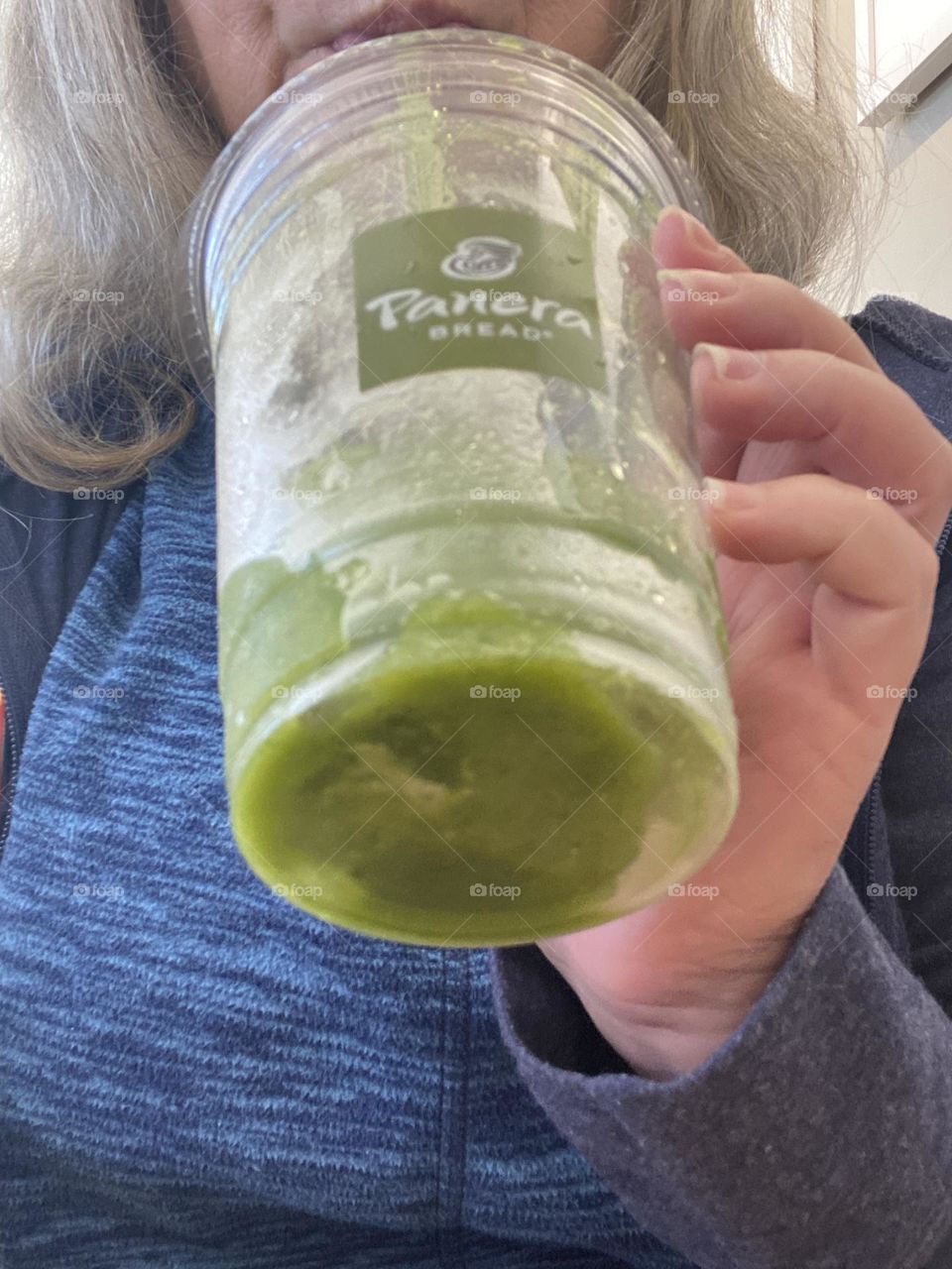A woman (myself) enjoying a green smoothie from Panera Bread. It is made from peach and mango purees, white grape and passionfruit concentrates blended with fresh spinach and ice. It’s a nice nutrition boost in the morning but also delicious.