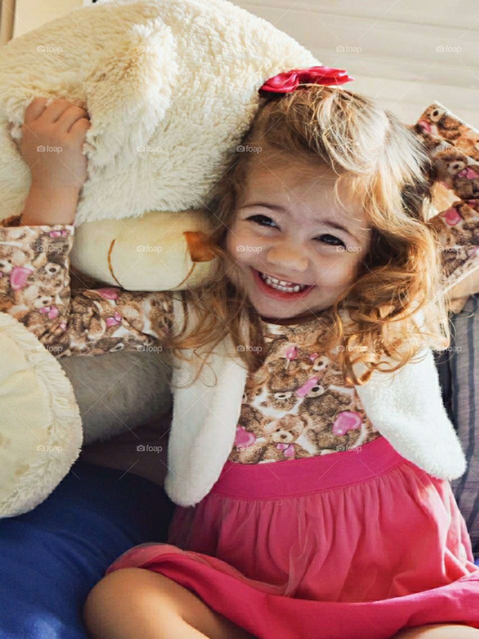 little girl hugging her teddy bear and smiling