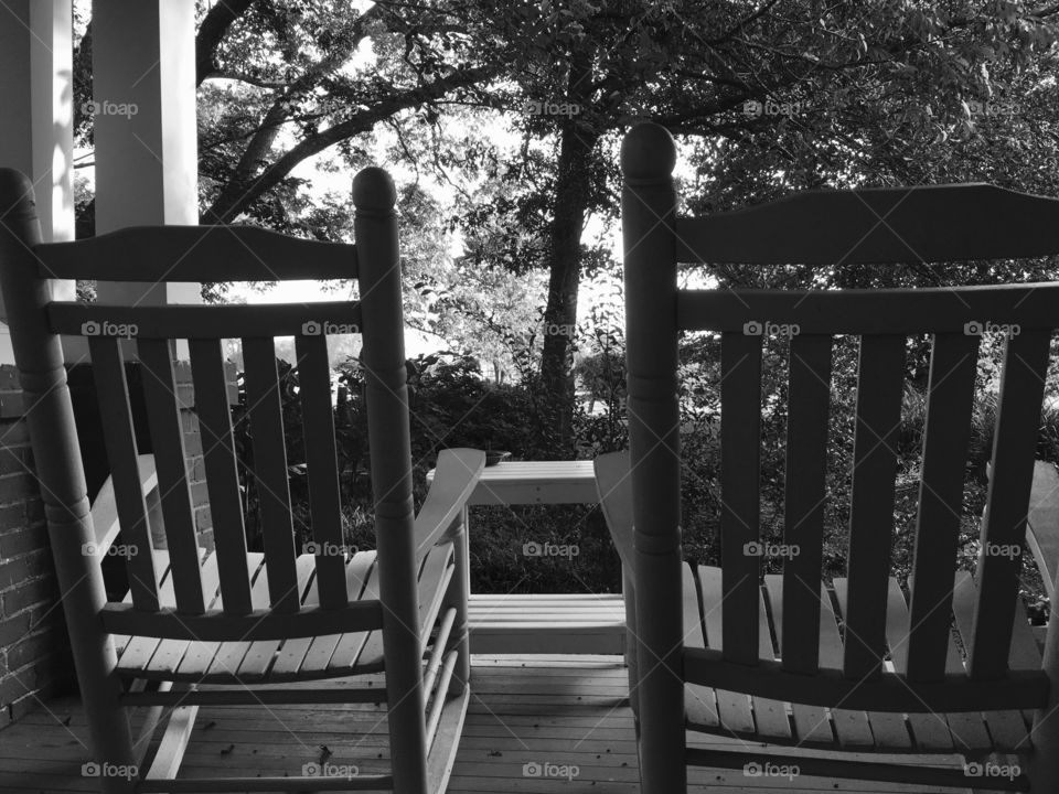 Black and white photo of rocking chair on porch.