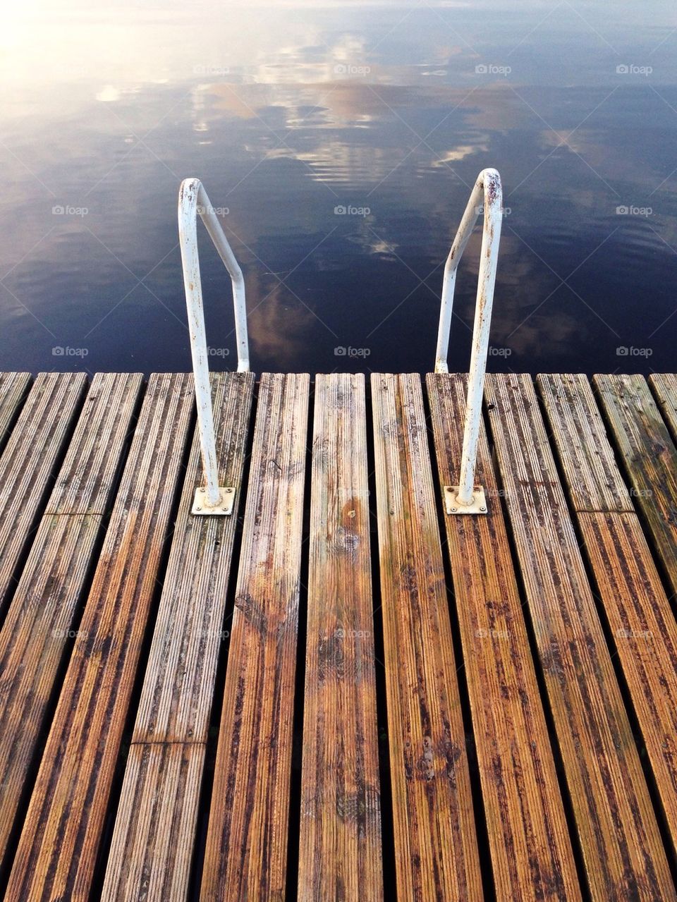 Wooden pier with white rail and sky reflected in the Valga River, Valga Estonia